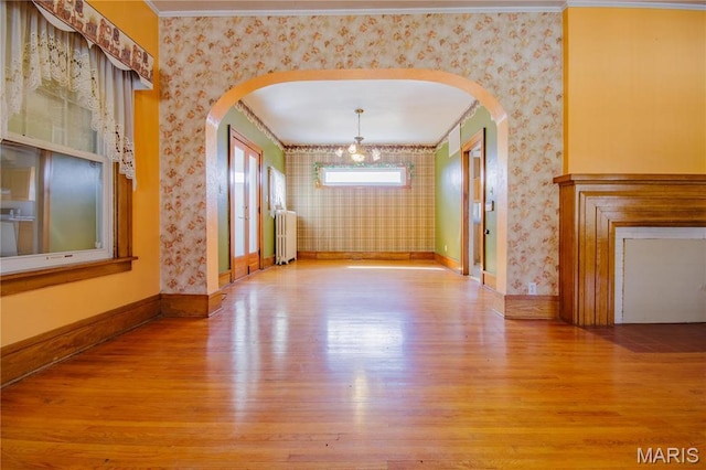 708 E Fillmore St E, Fillmore, IL 62032 - unfurnished living room with wallpapered walls, arched walkways, wood finished floors, radiator, and crown molding
