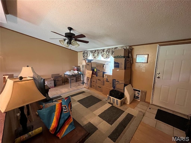 living room with a ceiling fan, a textured ceiling, and ornamental molding