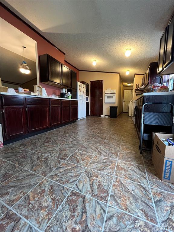 kitchen featuring white appliances, a textured ceiling, and dark brown cabinetry