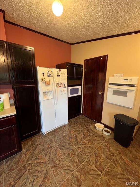 kitchen featuring white appliances, a textured ceiling, ornamental molding, light countertops, and dark brown cabinets