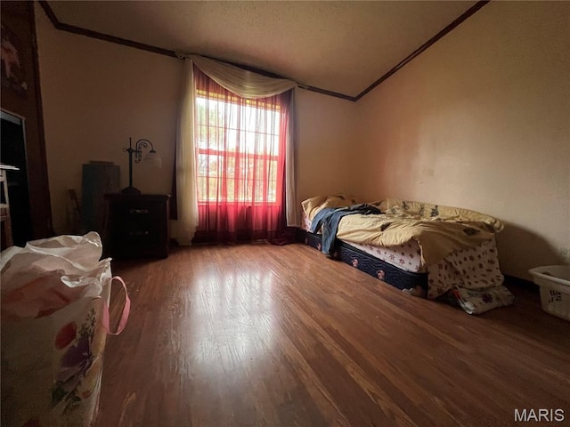 bedroom featuring crown molding, lofted ceiling, and wood finished floors