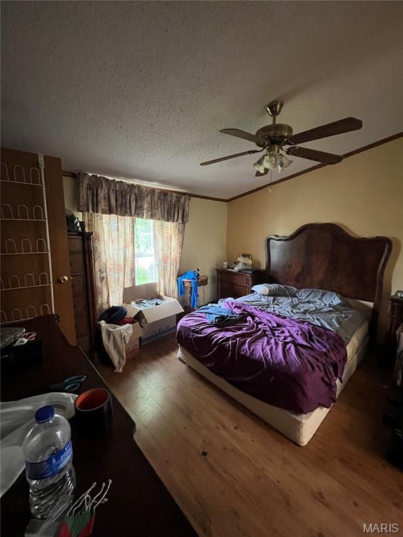 bedroom featuring wood finished floors, a ceiling fan, and a textured ceiling