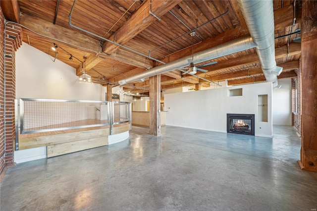 interior space featuring concrete floors, wood ceiling, a lit fireplace, baseboards, and beam ceiling