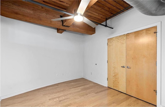unfurnished bedroom featuring light wood-style flooring, wood ceiling, beam ceiling, ceiling fan, and a closet