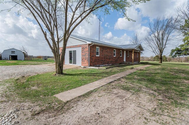 view of side of home with brick siding, an outdoor structure, and a yard