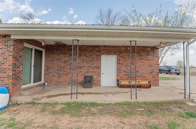 doorway to property featuring a patio area and brick siding