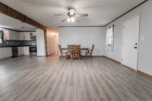 dining area with light wood finished floors, ceiling fan, baseboards, crown molding, and a textured ceiling