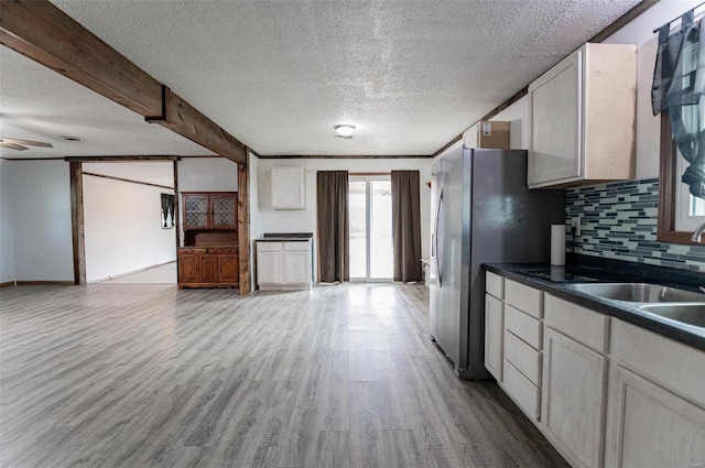 kitchen with dark countertops, wood finished floors, a textured ceiling, tasteful backsplash, and freestanding refrigerator