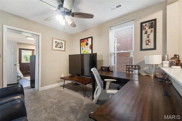 carpeted office space featuring a ceiling fan and baseboards