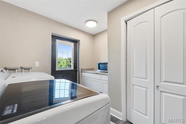 laundry area featuring washing machine and clothes dryer, cabinet space, and baseboards