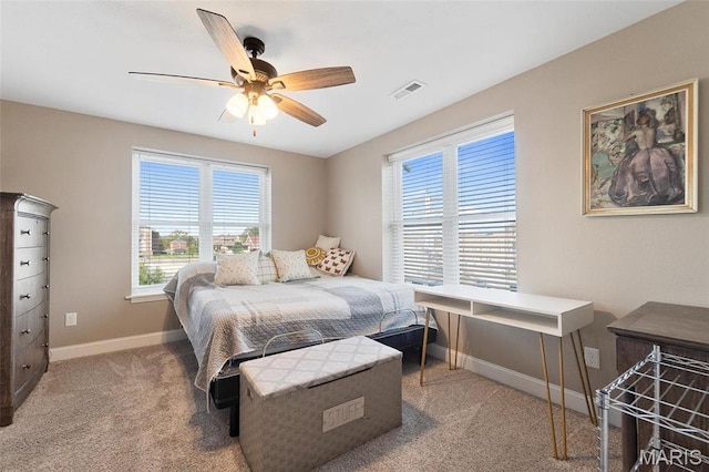 carpeted bedroom featuring multiple windows, baseboards, and a ceiling fan