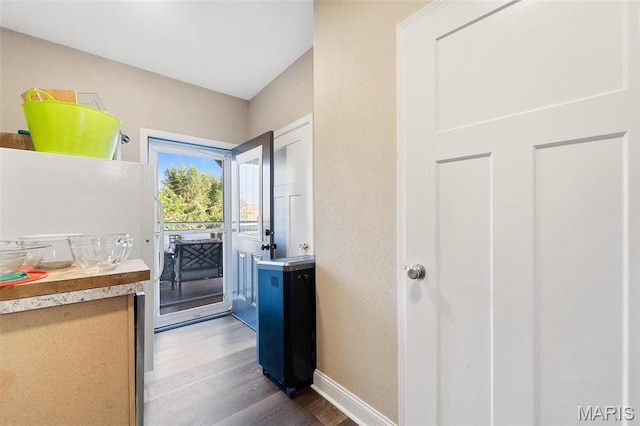 doorway with wood finished floors and baseboards