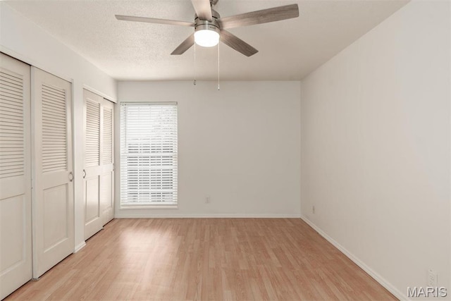 13555 Coliseum Dr Unit G, Chesterfield, MO 63017 - unfurnished bedroom with light wood-type flooring, multiple closets, baseboards, and a textured ceiling