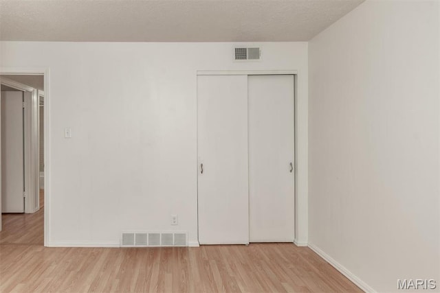 13555 Coliseum Dr Unit G, Chesterfield, MO 63017 - unfurnished bedroom featuring wood finished floors, baseboards, a closet, and a textured ceiling
