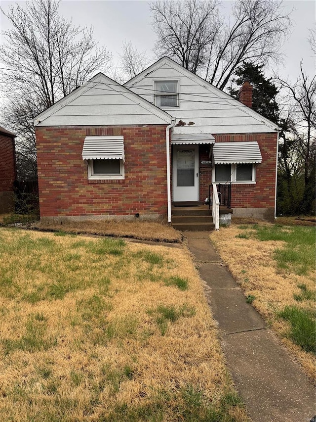 6859 Stratford Ave, Pine Lawn, MO 63121 - bungalow featuring brick siding, a front lawn, and a chimney