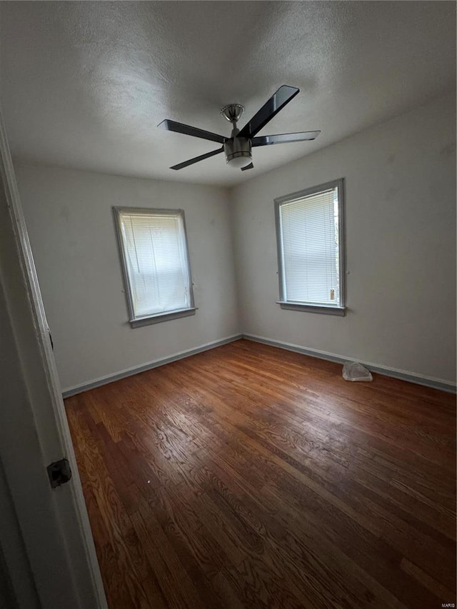 6859 Stratford Ave, Pine Lawn, MO 63121 - empty room with plenty of natural light, a ceiling fan, wood finished floors, a textured ceiling, and baseboards