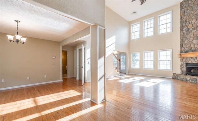 10625 Pine Needle Cir, Rolla, MO 65401 - unfurnished living room with stairs, hardwood / wood-style floors, a chandelier, a fireplace, and a high ceiling