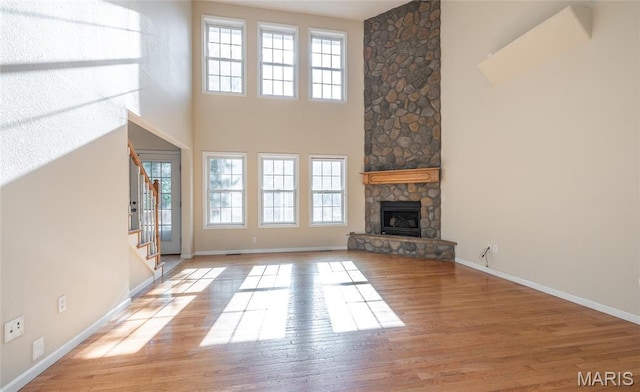 10625 Pine Needle Cir, Rolla, MO 65401 - unfurnished living room with wood finished floors, a stone fireplace, baseboards, and a high ceiling