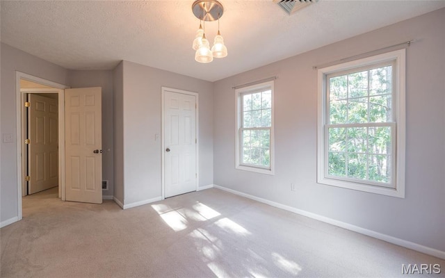 10625 Pine Needle Cir, Rolla, MO 65401 - unfurnished bedroom featuring light colored carpet, baseboards, a textured ceiling, and a chandelier
