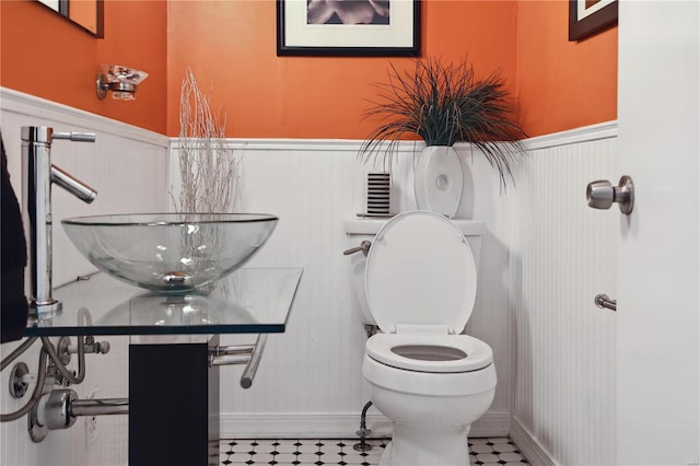 3944 Russell Blvd, Saint Louis, MO 63110 - bathroom featuring wainscoting, toilet, baseboards, and a sink