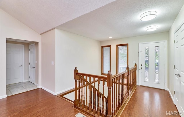entryway featuring wood finished floors, baseboards, and a textured ceiling