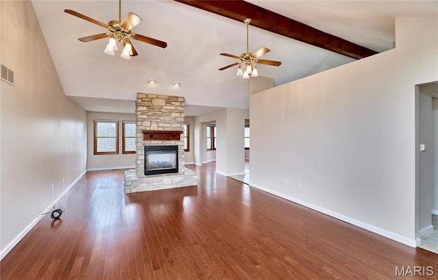 unfurnished living room with ceiling fan, high vaulted ceiling, a stone fireplace, wood finished floors, and baseboards