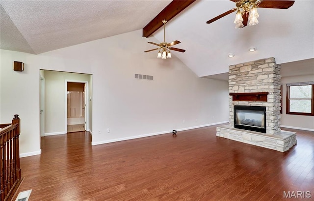 unfurnished living room featuring a ceiling fan, wood finished floors, a fireplace, beamed ceiling, and baseboards