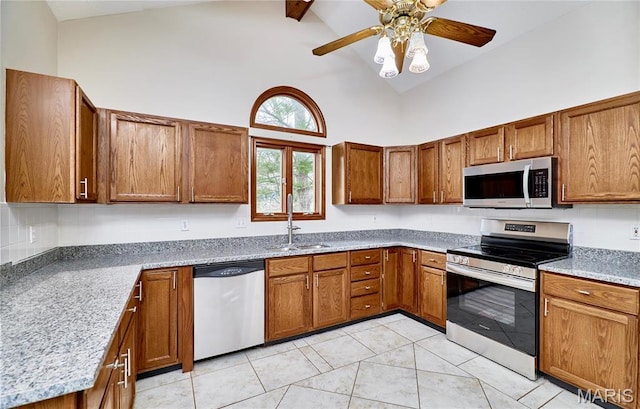 kitchen featuring stainless steel appliances, a sink, high vaulted ceiling, brown cabinets, and beam ceiling