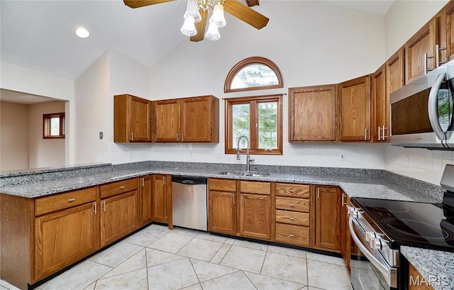 kitchen featuring appliances with stainless steel finishes, a sink, ceiling fan, high vaulted ceiling, and brown cabinetry