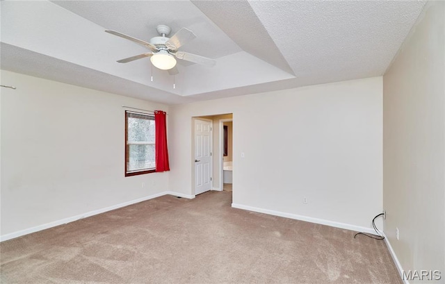 spare room with carpet, ceiling fan, baseboards, and a raised ceiling