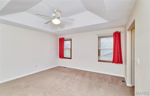 spare room featuring light carpet, a ceiling fan, baseboards, and a textured ceiling