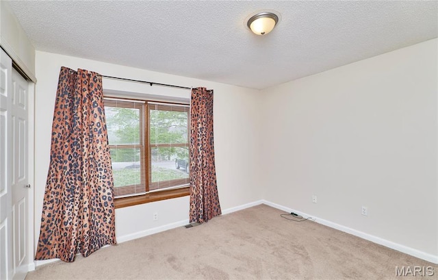 carpeted empty room featuring baseboards and a textured ceiling
