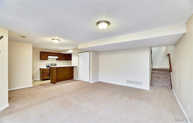 unfurnished living room featuring a textured ceiling, light colored carpet, stairs, and baseboards