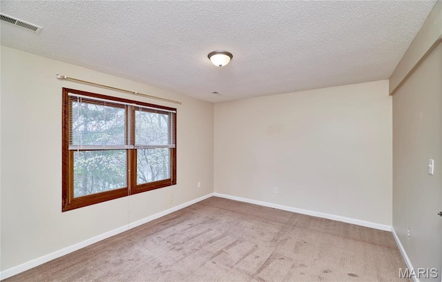 carpeted empty room featuring a textured ceiling and baseboards