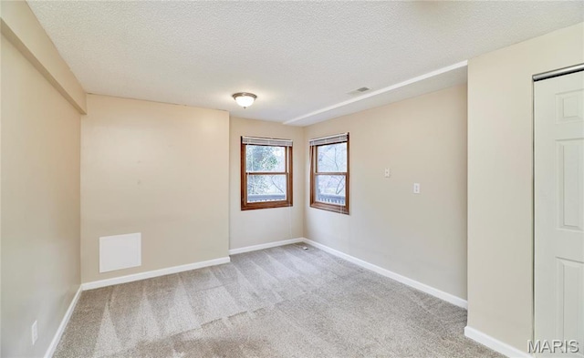 carpeted spare room with a textured ceiling and baseboards