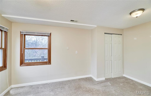 unfurnished bedroom with light colored carpet, a closet, baseboards, and a textured ceiling