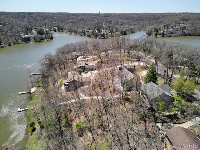 view of property location with a nearby body of water and a heavily wooded area