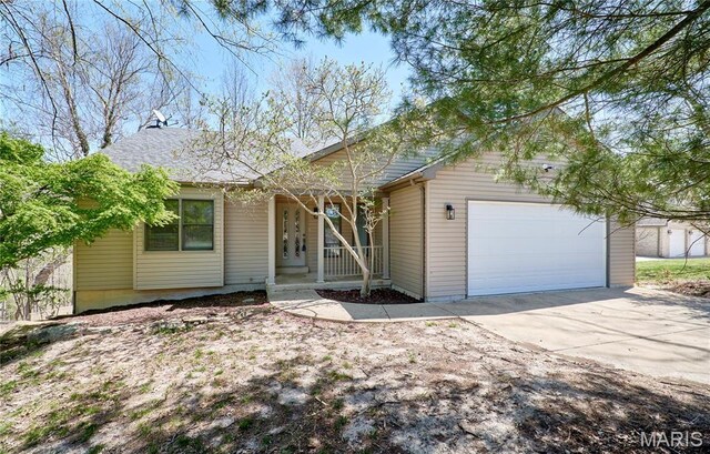 view of front of property with covered porch, a garage, and driveway