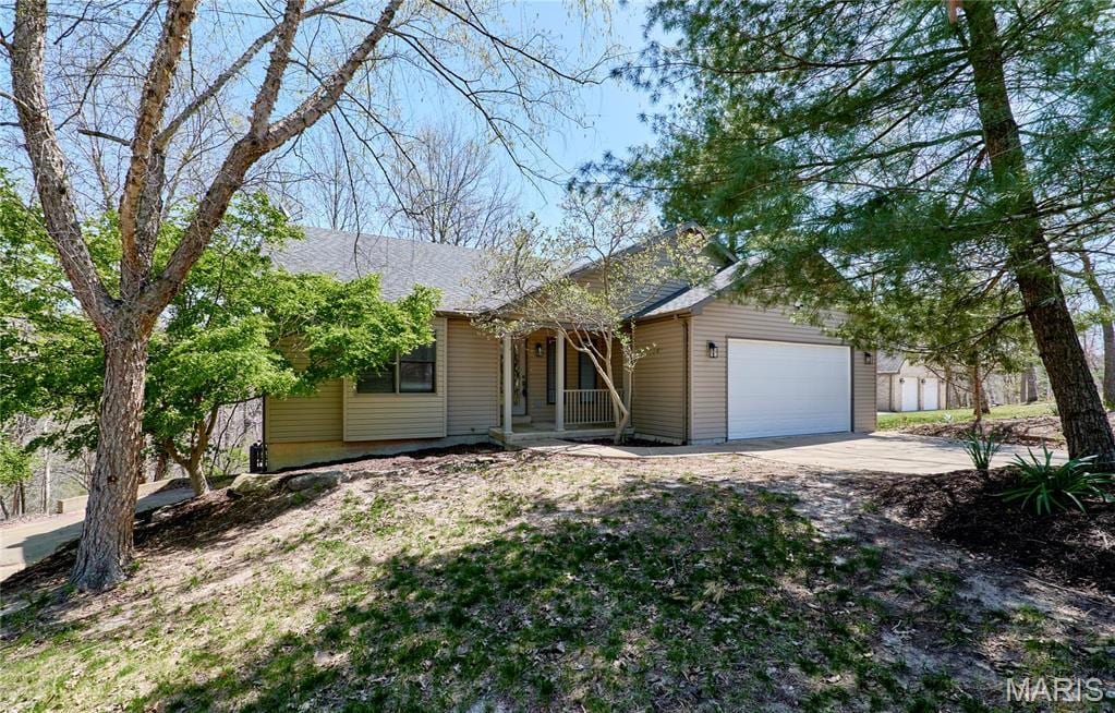 157 S Kings Rd, Lake Sherwood, MO 63357 - view of front of home featuring covered porch, a garage, and concrete driveway