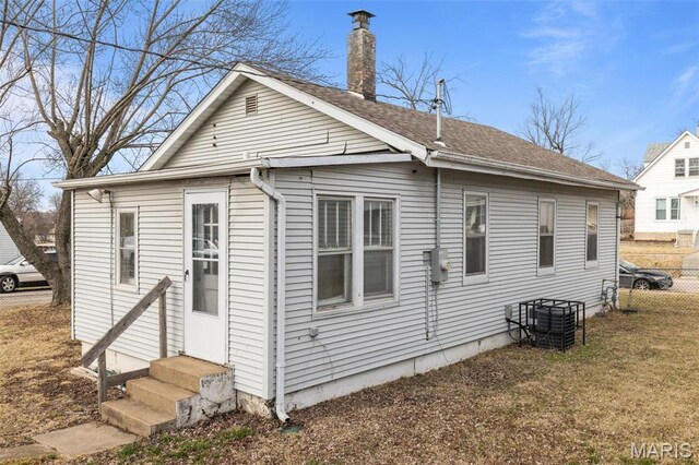 6546 Joseph Ave, Saint Louis, MO 63133 - back of property featuring entry steps, a chimney, a shingled roof, and central AC unit