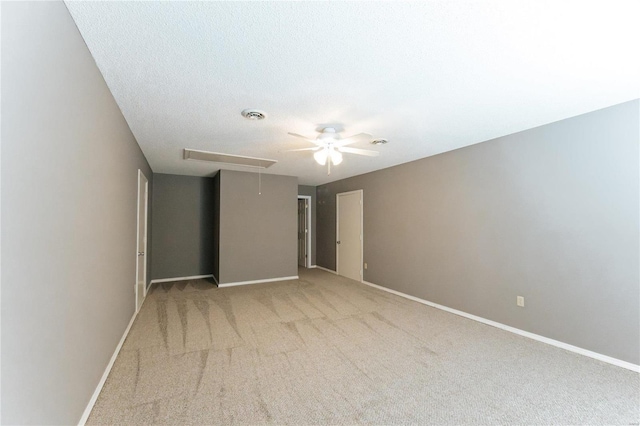 spare room with attic access, ceiling fan, light colored carpet, and baseboards