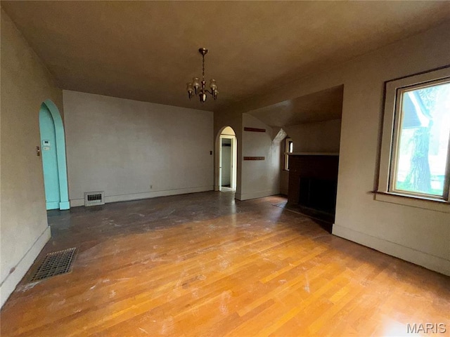 1548 Highland Ave, Alton, IL 62002 - unfurnished living room featuring arched walkways, a fireplace, wood finished floors, a chandelier, and baseboards