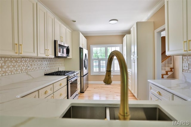 409 Country Club Vw, Edwardsville, IL 62025 - kitchen with appliances with stainless steel finishes, a sink, decorative backsplash, light wood finished floors, and light stone countertops