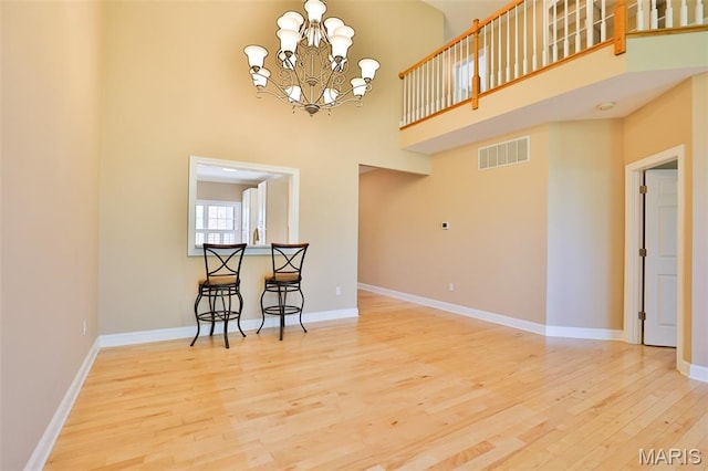 409 Country Club Vw, Edwardsville, IL 62025 - unfurnished dining area featuring wood finished floors, a chandelier, a high ceiling, and baseboards