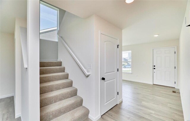 staircase with wood finished floors, baseboards, and recessed lighting