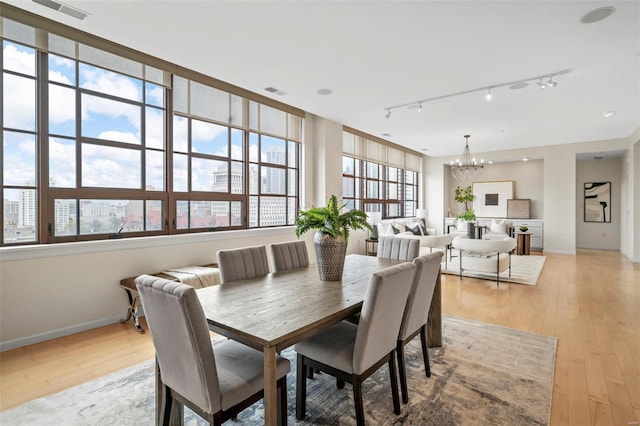 dining space with track lighting, a chandelier, light wood-type flooring, and baseboards