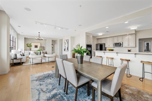 dining space featuring rail lighting, light wood finished floors, a chandelier, recessed lighting, and baseboards