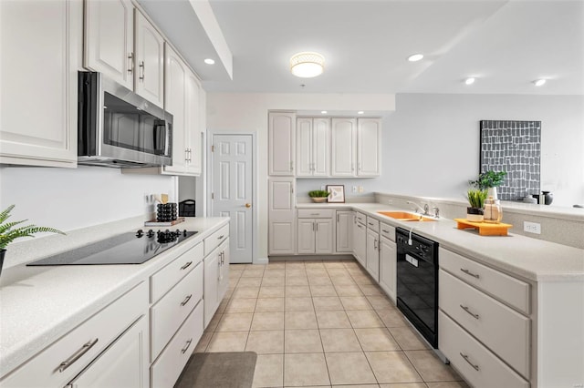 kitchen featuring black appliances, a sink, a peninsula, light tile patterned flooring, and light countertops