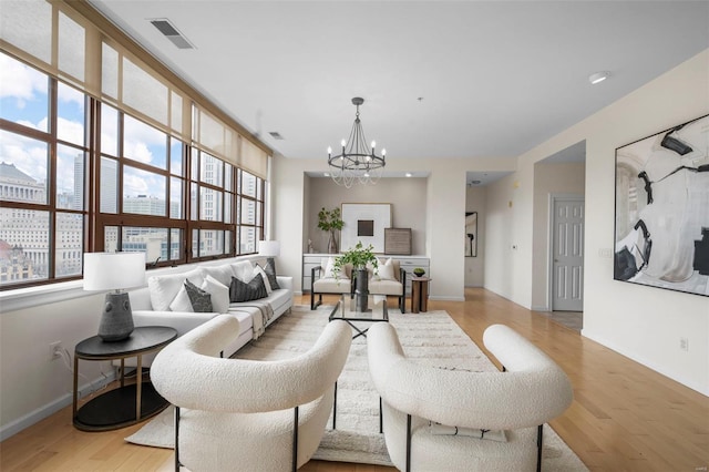 living room with a chandelier, light wood-type flooring, and baseboards