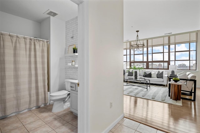 bathroom with tile patterned floors, a chandelier, toilet, curtained shower, and vanity